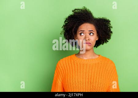 Photo of stressed young wavy hairdo lady look promo wear orange pullover isolated on green color background Stock Photo