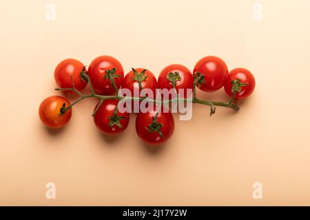 Directly above view of fresh red cherry tomatoes twig on pink background Stock Photo