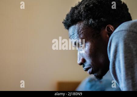 A photo of a young man sitting and looking at a computer screen Stock Photo