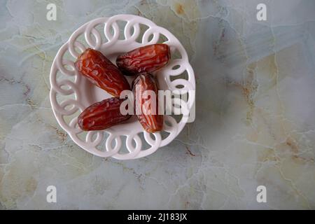 Date fruit in bowl on colorful marble background, top view Stock Photo