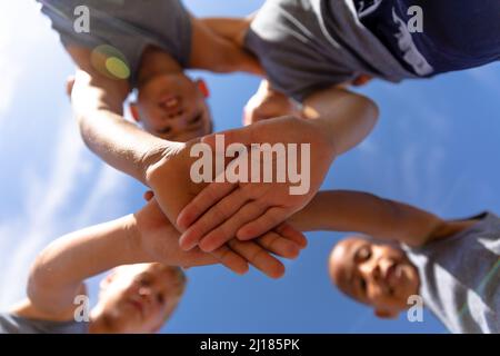 Directly below shot of multiracial elementary schoolboys stacking hands during soccer match Stock Photo