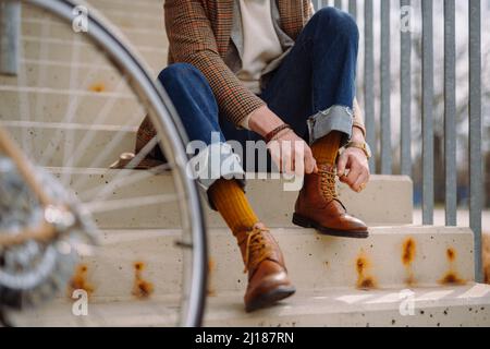 Businessman putting on elegant leather shoes. Preparing for bicycle ride.  Stock Photo