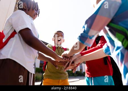 Multiracial schoolboys stacking hands while standing in school campus Stock Photo