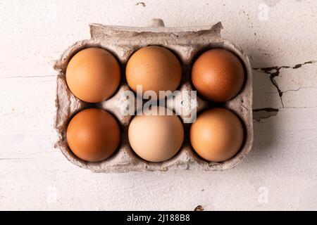 Directly above view of fresh brown eggs arranged in carton white wooden table Stock Photo
