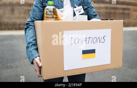 Volunteer collecting box with donations for Ukrainian refugees - Humanitarian aid for Ukraine Stock Photo