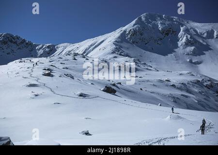 Hiking in winter following a snow trail towards Retezat peak. Photo taken on 12th March 2022 near Stevia Lake, Carpathian Retezat Mountains, Romania. Stock Photo