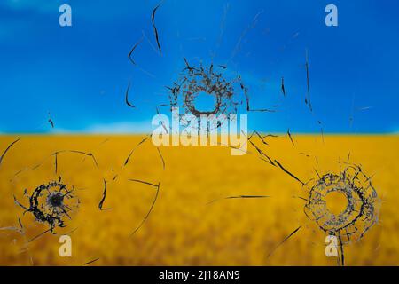 War threat concept. Hole in the glass from a bullet on the background of the flag of Ukraine Stock Photo