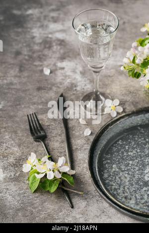 Spring place table setting with blossoming apple tree branches and flowers on grey table. Holidays decoration on Provence style. Romantic dinner. Over Stock Photo