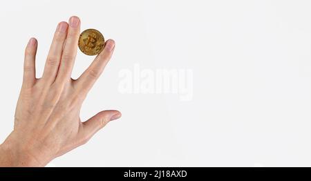 Hand with bitcoin coin in hand between fingers. Financial tricks, cryptocurrency investing on banner with copy space. High quality photo Stock Photo