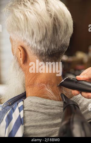 Hairdresser making stylish haircut for old man Stock Photo