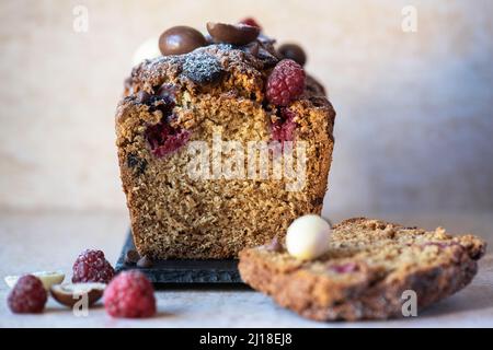 Sliced vanilla cake with chocolates and raspberry.  Close up. Stock Photo