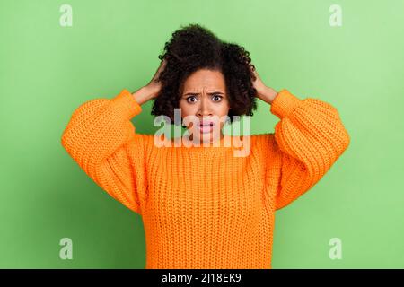 Photo of sad young volume hairdo lady hands head wear orange jumper isolated on green color background Stock Photo