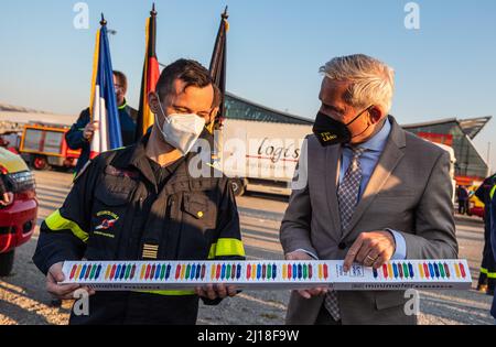 Stuttgart, Germany. 23rd Mar, 2022. Thomas Strobl (r, CDU), Minister of the Interior of Baden-Württemberg, presents Colonel Jean-Philippe Nicot, head of operations of the French Civil Protection (Securite Civile), with chocolate as a guest gift at the trade fair center in Stuttgart. Colonel Nicot and his team are part of an aid convoy heading for Ukraine, which is making an overnight stop in Stuttgart. Credit: Christoph Schmidt/dpa/Alamy Live News Stock Photo