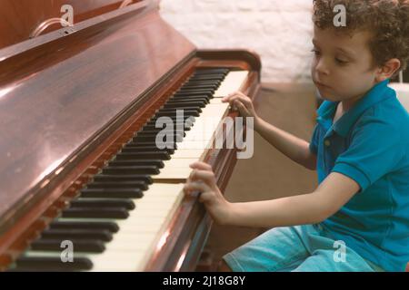 Beautiful little kid boy playing piano in living room Stock Photo