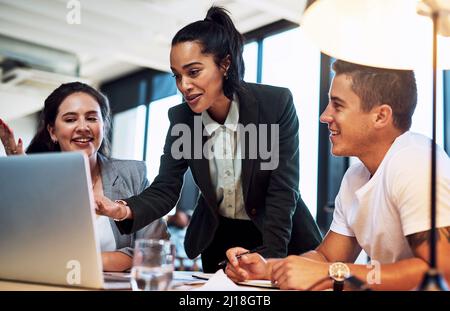 This right here is our winning idea. Shot of a group of businesspeople working together on a laptop in an office. Stock Photo