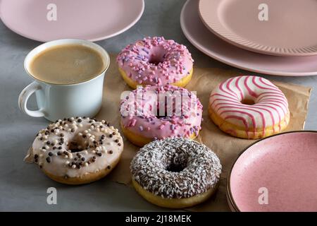 Several donuts lie on craft parchment paper on gray surface Stock Photo