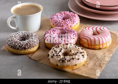 Several donuts lie on craft parchment paper on gray surface Stock Photo
