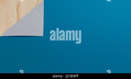 Folded blue paper on top of plywood. Textured paper and wood background with copy space. 4k resolution. Stock Photo