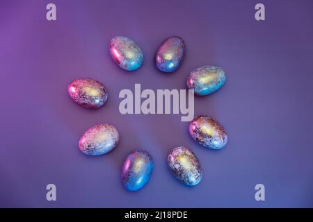 Top view round frame made of Easter golden eggs with different patterns in neon colors light. Purple very peri color minimalist festive background. Mo Stock Photo