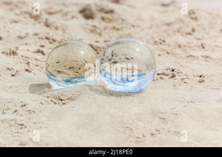 Crystal balls on sand with reflections of blue sky Stock Photo