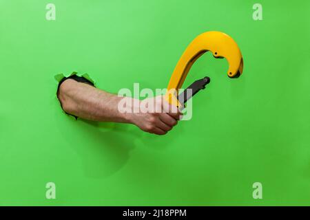 A man holds a tool for cutting plastic pipes on a green background Stock Photo