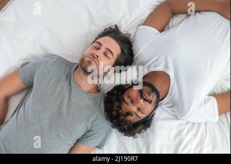 Two young men sleeping on their backs in bed Stock Photo