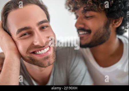 Curly-haired guy gazing at his handsome boyfriend Stock Photo