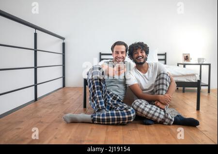 Two joyous men using the cellphone for channel-surfing Stock Photo