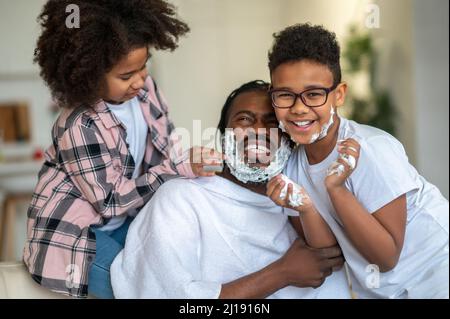 Man in towel with foam on face and children Stock Photo