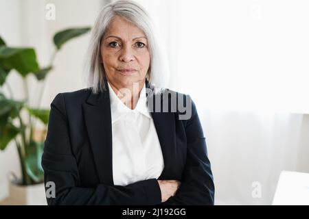 Senior woman working inside modern office - Focus on face Stock Photo