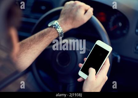 Waiting for his navigation to commence. Cropped shot of a unrecognizable man using his phone while driving to a destination. Stock Photo