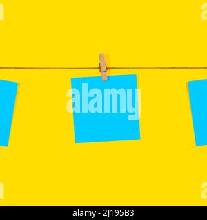 Blue Note papers and decorative pin or clip isolated on yellow background. Office mock up. Top view, flat lay. Colorful office note or sticker papers Stock Photo