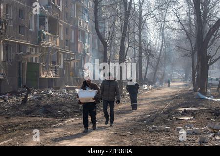 Mariupol, Ukraine. 23rd Mar, 2022. Men emerge to procure supplies in their still burning neighbourhood in the city. The battle between Russian/Pro Russian forces and the defencing Ukrainian forces lead by Azov battalion continues in the port city of Mariupol. Credit: SOPA Images Limited/Alamy Live News Stock Photo