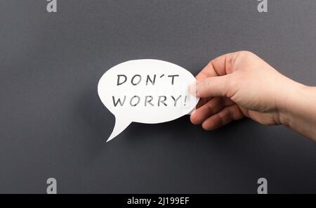 Don´t worry is standing on a speech bubble, hand holds the message, positive message, no problems Stock Photo