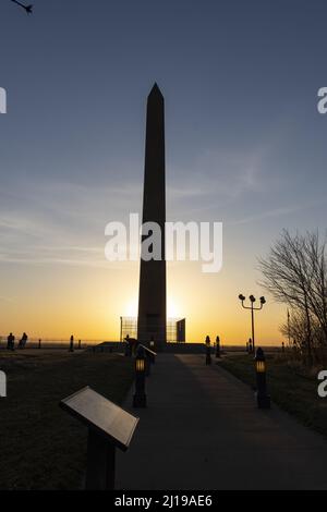 A vertical shot of the silhouette of the Sergeant Floyd Monument against a sunrise sky in Iowa Stock Photo