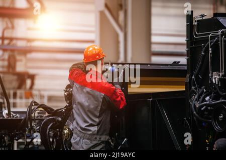 Industrial workers assembles agricultural harvester in workshop. Stock Photo