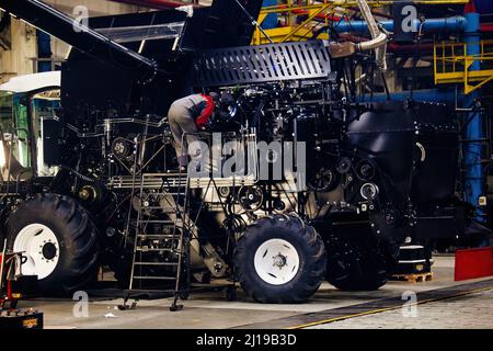 Industrial workers assembles agricultural harvester in workshop. Stock Photo