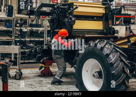 Industrial workers assembles agricultural harvester in workshop. Stock Photo