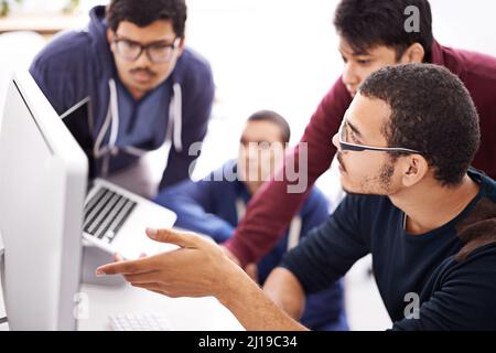 Collaborative coding. Shot of a group of colleagues working together with a computer in an office. Stock Photo