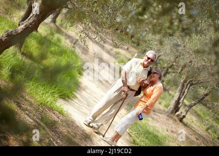 Enjoying a leisurely stroll through the woods. A senior couple walking together along a forest trail. Stock Photo