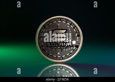 Solana SOL Physical Coin Placed on Reflective Surface and lit with green light Stock Photo