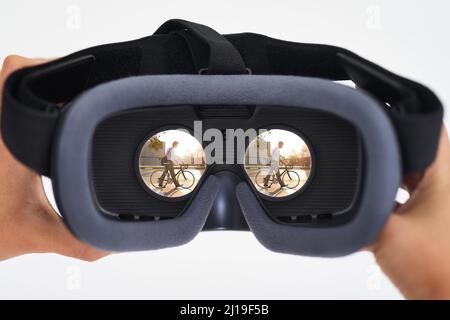 The age of virtual reality is here. Shot of a person holding a VR headset with a man riding a bicycle seen in the lenses. Stock Photo