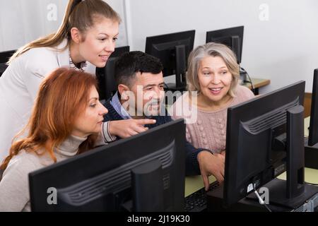 Young and mature business people grouped around computer monitor Stock Photo