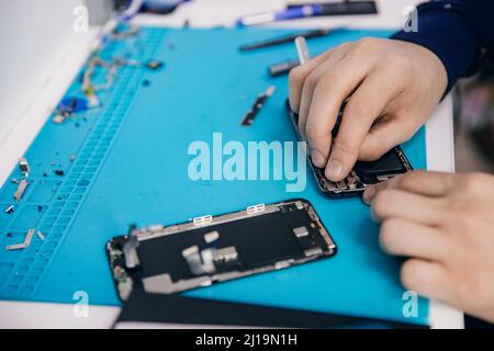Repair modern mobile phone, master disassembles case to replace broken screen. Stock Photo