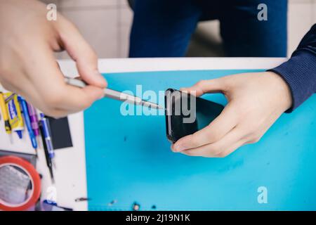 Repair modern mobile phone, master disassembles case to replace broken screen. Stock Photo