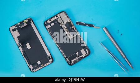 Repair modern mobile phone, master disassembles case to replace broken screen or replacement battery degradation top view. Stock Photo