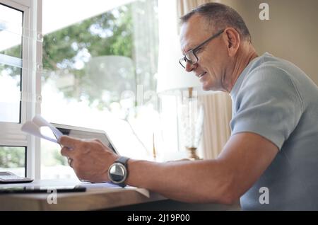 Making sure all of the details are in order. Shot of a mature man reading over financial documents while working. Stock Photo