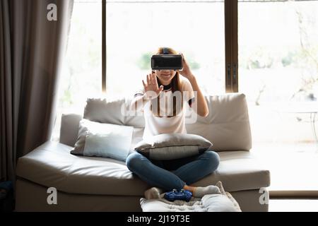 Concept of technology,gaming,entertainment and people.asian woman enjoying virtual reality glasses while relaxing in living room.Happy young guy with Stock Photo