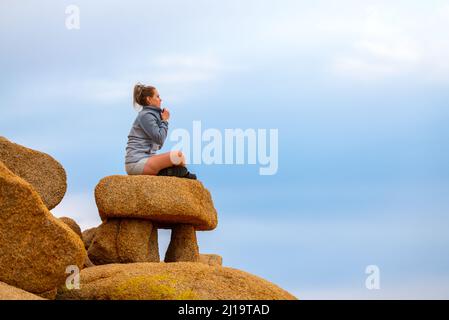 Woman tourist seen in Joshua Tree National Park waiting for sunset views over the desert landscape. Stock Photo