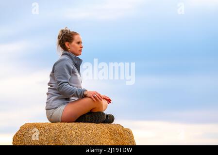 Woman tourist seen in Joshua Tree National Park waiting for sunset views over the desert landscape. Stock Photo
